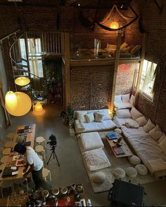 a living room filled with lots of furniture next to a brick wall covered in windows