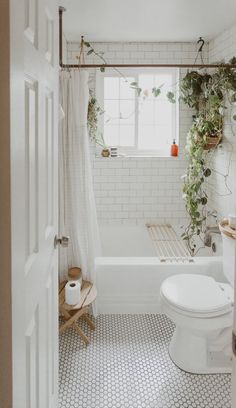 a bathroom with a toilet, tub and plants on the wall