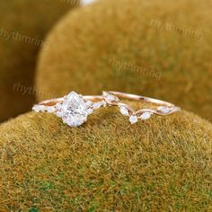 two engagement rings sitting on top of a mossy surface