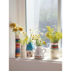 three vases filled with yellow flowers sitting on a window sill