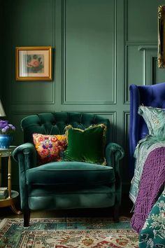 a bedroom with green walls, blue chair and floral bedding on the floor in front of it