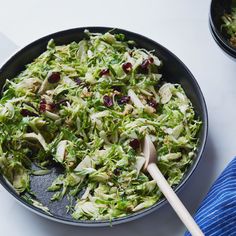 a bowl filled with shredded lettuce and cranberries on top of a table