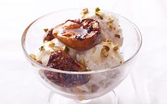 a glass bowl filled with fruit and nuts on top of a white tablecloth covered table