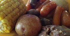 a yellow plate topped with meat, potatoes and corn on the cob covered in gravy