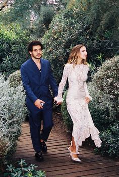 a man and woman walking down a wooden walkway