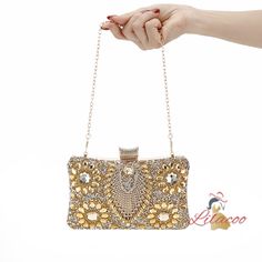 Possessing a handbag like this is a true testament to your exquisite taste and love for luxury. This dazzling clutch is designed to be the centerpiece of any glamorous ensemble. Its surface is encrusted with meticulously placed crystals and gems, creating a radiant, eye-catching effect that sparkles with every movement. The intricate floral patterns made from golden stones add a layer of sophistication and timeless elegance. The top clasp is equally adorned, ensuring that every detail of this ha Luxury Clutch With Mobile Phone Bag For Parties, Luxury Clutch For Party With Mobile Phone Bag, Luxury Party Clutch With Mobile Phone Bag, Luxury Gold Clutch For Mobile Phone, Luxury Gold Evening Bag With Phone Holder, Luxury Gold Evening Bag With Mobile Phone Holder, Gold Evening Shoulder Bag With Mobile Phone Pocket, Gold Evening Shoulder Bag For Mobile Phone, Glamorous Handheld Clutch