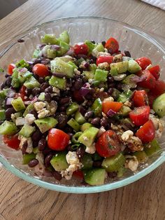 a salad in a glass bowl on top of a wooden table