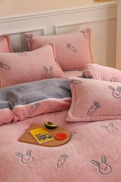 a bed covered in pink sheets and pillows with bunny drawings on the comforter set