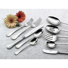 an assortment of silverware on a white tablecloth with a flower in the middle