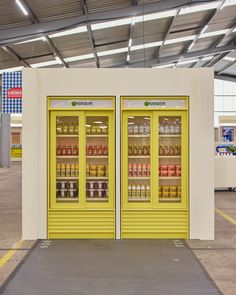 two yellow vending machines sitting inside of a building with lots of bottles in them