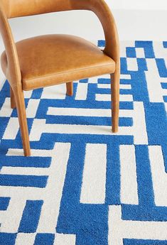 a brown leather chair sitting on top of a blue and white rug