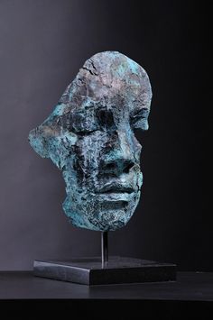 a bronze head is shown on a black stand with a dark background and the image shows it's face