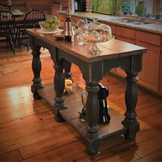 an island in the middle of a kitchen with wine glasses and fruit on it,