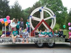 a group of people sitting on the back of a truck with balloons in the shape of a peace sign