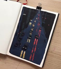 an open book with cars driving down the road at night time, on a wooden table