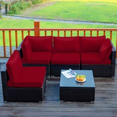 a red couch sitting on top of a wooden deck next to a table with fruit