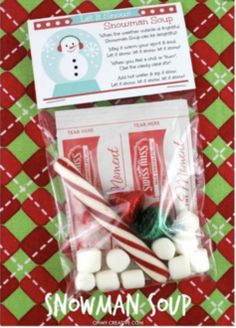 some candy canes and marshmallows in a bag on a red and green tablecloth