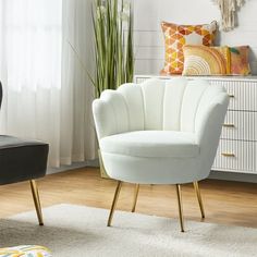 a white chair sitting on top of a wooden floor next to a black chair with gold legs