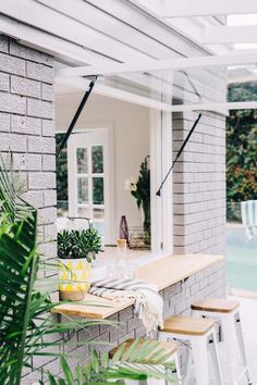 an outdoor table and chairs are set up outside by the swimming pool with greenery