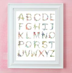 the alphabet is made up of flowers and letters, all in white frame on pink wall