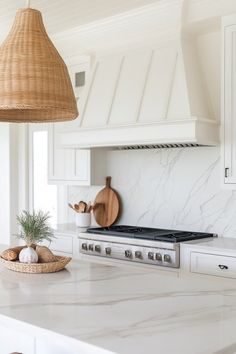 a kitchen with marble counter tops and white cabinets, hanging lights over the stove top