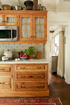 a kitchen area with wooden cabinets and white walls, including a red rug on the floor