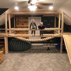 two people standing on top of a wooden structure in a room with carpeted flooring