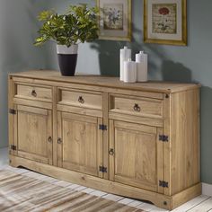 a large wooden cabinet with two vases on top and one potted plant in the corner