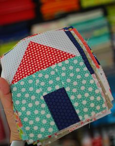 a person holding up a small patchwork house