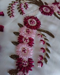 pink flowers and leaves on white fabric with gold trimming around the edges, along with other decorative items