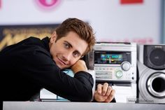 a man leaning on a boombox with his hand on his chin and looking at the camera