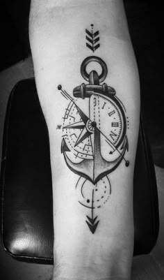 a black and white photo of a compass with an anchor tattoo on the arm,