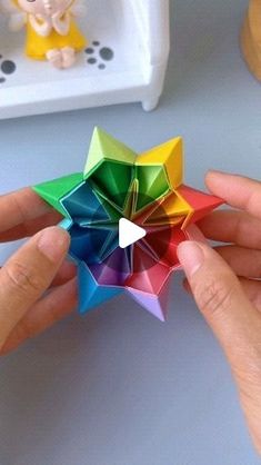 someone is holding a colorful origami star