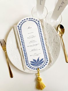 a plate with a menu on it next to silverware and gold utensils