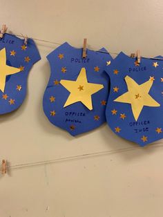 three police badges with stars on them hanging from clothes pins and pinned to the wall