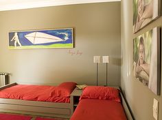 two twin beds in a small room with pictures on the wall and red rugs