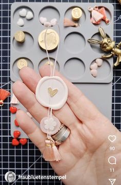 a hand holding a small white and gold clock ornament with hearts on it