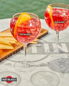 two wine glasses filled with fruit sitting on top of a table next to each other