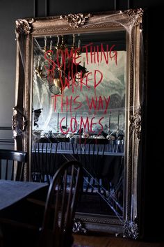 a mirror with writing on it sitting in front of a dining room table and chairs