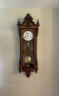 a wooden clock mounted to the side of a wall