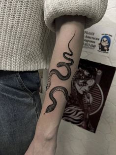 a woman's arm with a snake tattoo on the left side of her arm