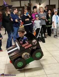 a group of people standing around and watching a boy in a car costume