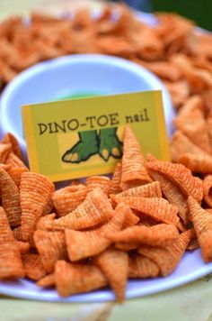 a plate full of orange cheetos sitting on top of a table with a sign that says dino - toe nail