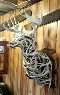 a deer head made out of antlers hanging from the side of a wooden wall