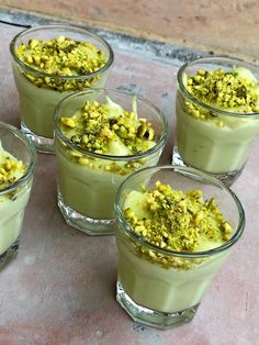 four glasses filled with dessert sitting on top of a table