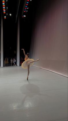 a ballerina is dancing in the middle of an empty room with columns and lights