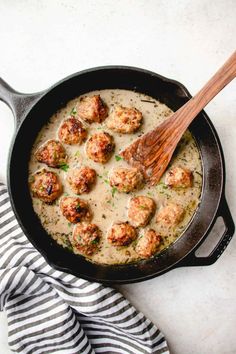 a skillet filled with meatballs and gravy on top of a table