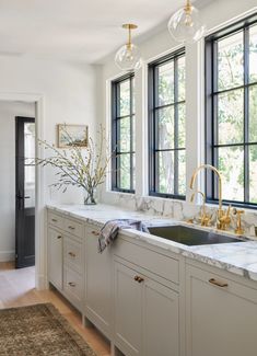 a kitchen with marble counter tops and gold faucets in the window sill