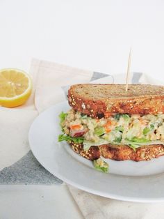 a sandwich with lettuce, carrots and other toppings on a white plate