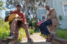 two men sitting on brick steps in front of a house